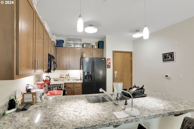 kitchen with light stone counters, decorative light fixtures, brown cabinetry, a peninsula, and black appliances