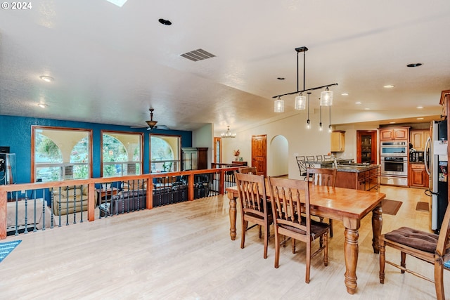 dining area with ceiling fan with notable chandelier, light wood-type flooring, and sink