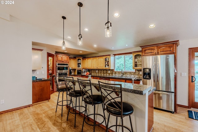 kitchen with a kitchen island, a breakfast bar, stainless steel appliances, and light hardwood / wood-style flooring