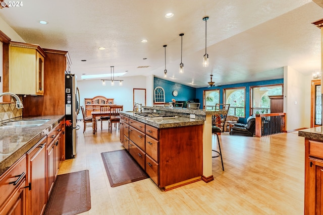 kitchen with light wood-type flooring, a breakfast bar, sink, pendant lighting, and appliances with stainless steel finishes