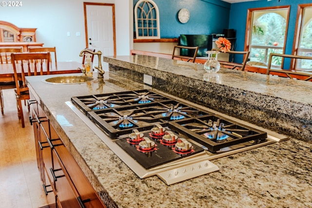 kitchen featuring stone countertops, sink, hardwood / wood-style floors, and stainless steel gas cooktop