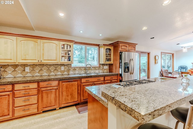 kitchen with light wood-type flooring, a breakfast bar, sink, stainless steel appliances, and a center island