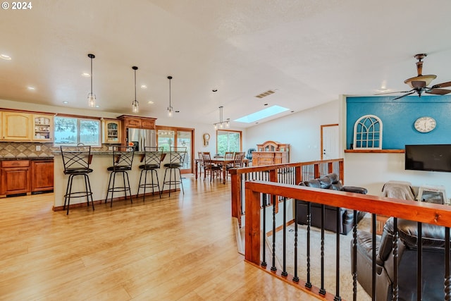 interior space with stainless steel refrigerator with ice dispenser, plenty of natural light, a breakfast bar area, and light hardwood / wood-style flooring