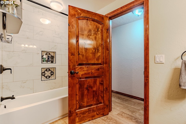 bathroom featuring hardwood / wood-style flooring, tiled shower / bath, and a textured ceiling