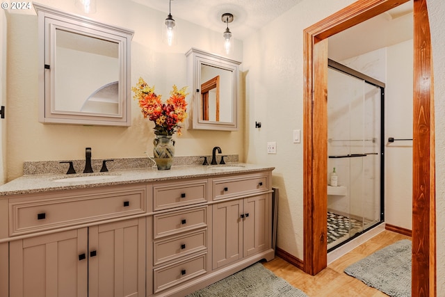 bathroom featuring hardwood / wood-style flooring, an enclosed shower, vanity, and a textured ceiling