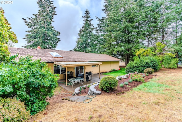 back of house with a patio and a lawn