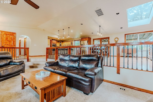 living room with light carpet, ceiling fan, and lofted ceiling with skylight