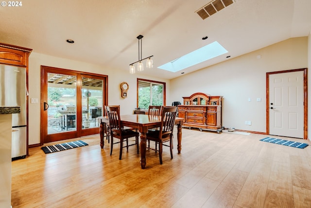 dining area with light hardwood / wood-style floors and lofted ceiling with skylight