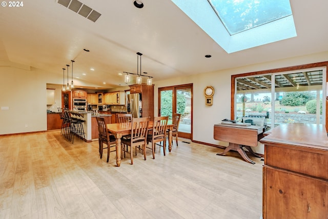 dining area with light wood-type flooring and lofted ceiling with skylight