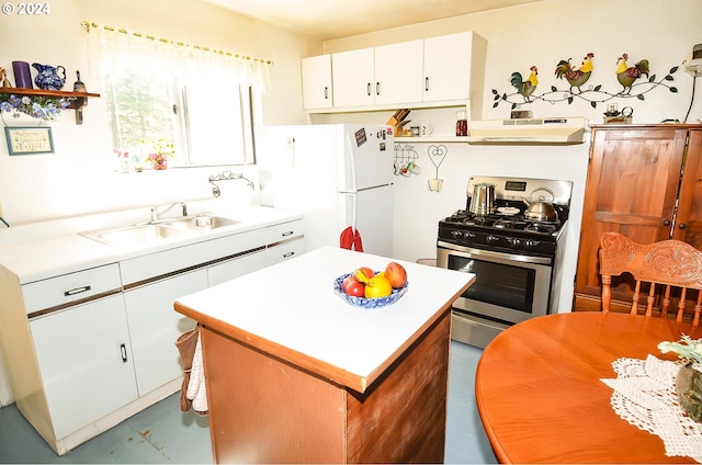 kitchen featuring under cabinet range hood, a sink, light countertops, freestanding refrigerator, and gas stove