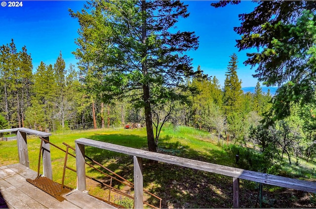 view of yard with a forest view and a wooden deck