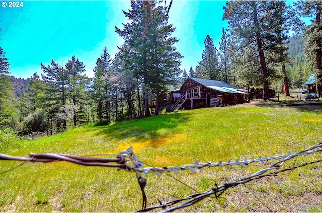 view of yard featuring a barn, a forest view, and an outdoor structure