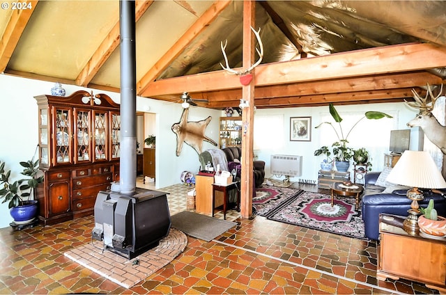 living room featuring a wood stove, vaulted ceiling with beams, stone finish flooring, and heating unit