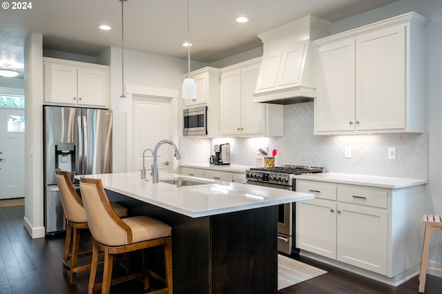 kitchen with sink, white cabinets, hanging light fixtures, a kitchen island with sink, and appliances with stainless steel finishes