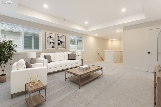 living room with light colored carpet, a raised ceiling, and plenty of natural light