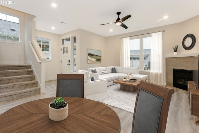 living room with ceiling fan, a tile fireplace, and light hardwood / wood-style flooring