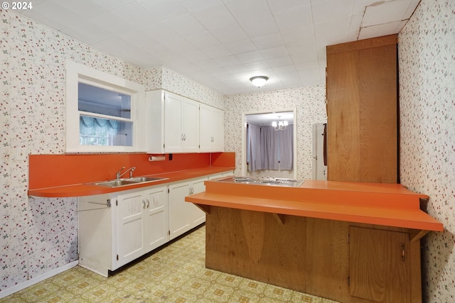 kitchen with stainless steel gas cooktop, sink, a breakfast bar, kitchen peninsula, and white cabinets