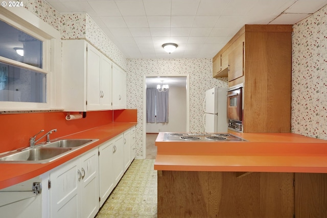 kitchen with white cabinetry, white refrigerator, sink, and stainless steel electric cooktop