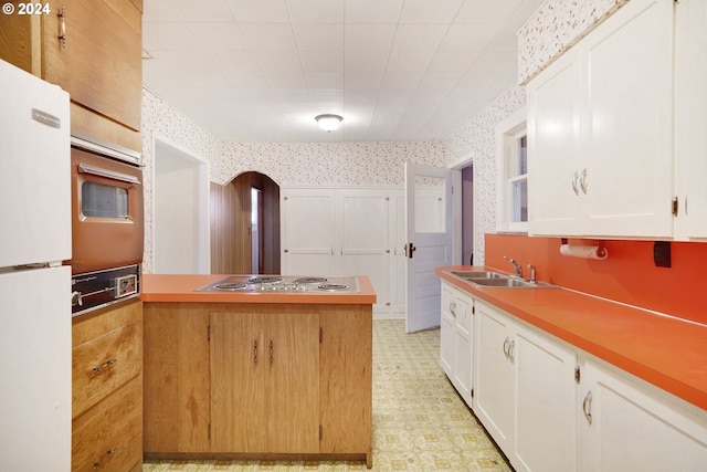 kitchen featuring white cabinets, stainless steel stovetop, sink, and white fridge