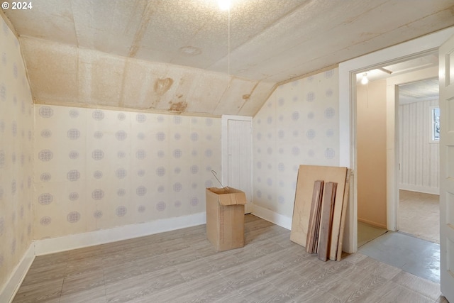 bonus room with wood-type flooring, a textured ceiling, and vaulted ceiling