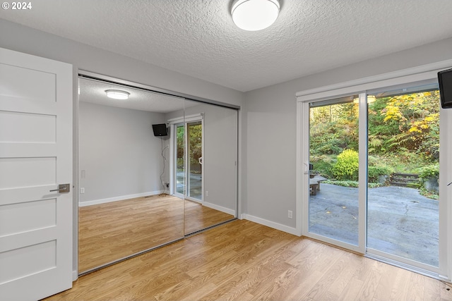 spare room featuring a healthy amount of sunlight, light hardwood / wood-style floors, and a textured ceiling