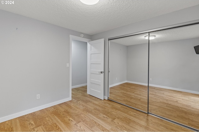 unfurnished bedroom featuring a closet, a textured ceiling, and light hardwood / wood-style floors