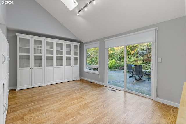 interior space with rail lighting and vaulted ceiling with skylight