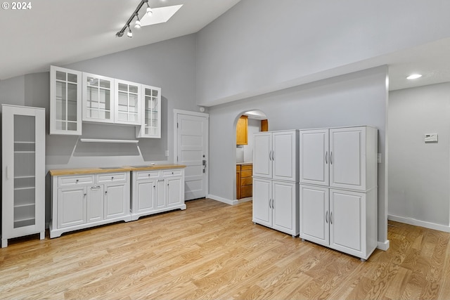 kitchen featuring high vaulted ceiling, light wood-type flooring, rail lighting, and white cabinets