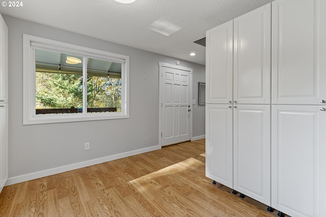 interior space with a textured ceiling and light hardwood / wood-style floors