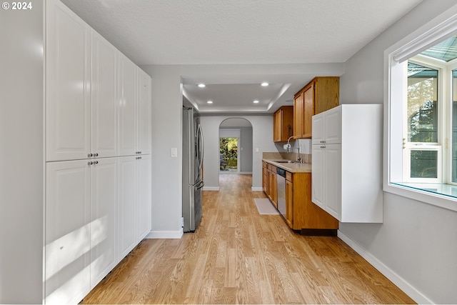 kitchen with appliances with stainless steel finishes, light hardwood / wood-style floors, and a textured ceiling