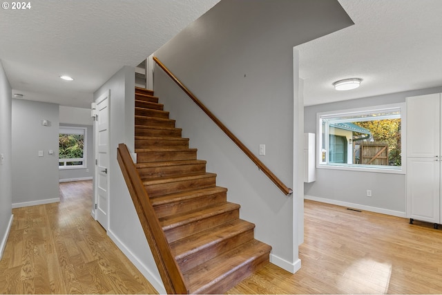 stairs featuring hardwood / wood-style flooring and a textured ceiling