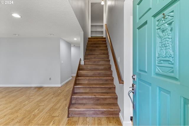 staircase featuring hardwood / wood-style flooring and a textured ceiling