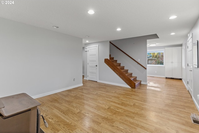 unfurnished living room featuring light hardwood / wood-style floors and a textured ceiling