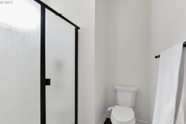 bathroom with a shower with shower door and toilet