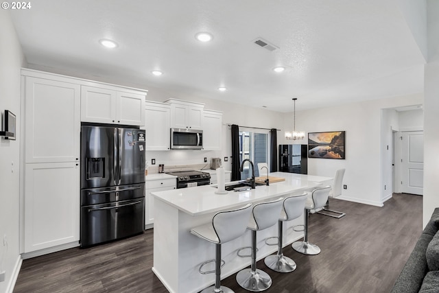 kitchen featuring a center island with sink, white cabinetry, stainless steel appliances, a breakfast bar area, and dark hardwood / wood-style flooring