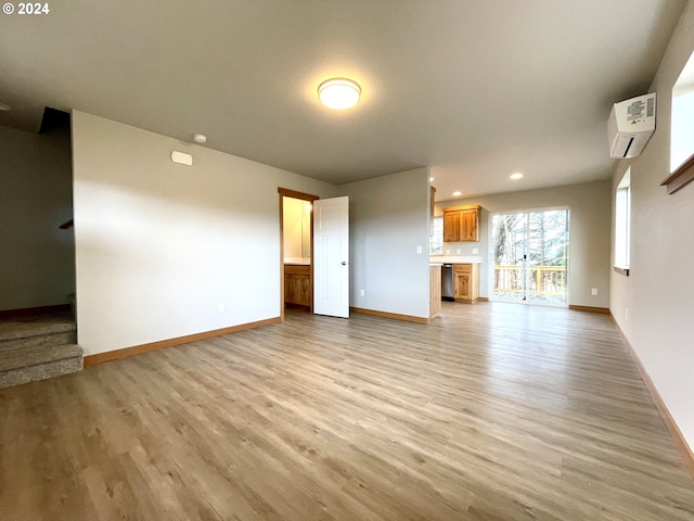 unfurnished living room with a wall mounted air conditioner and light hardwood / wood-style flooring