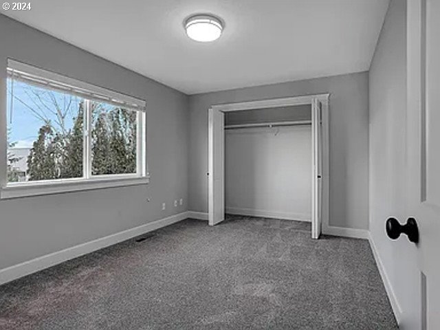 unfurnished bedroom featuring a closet and dark carpet