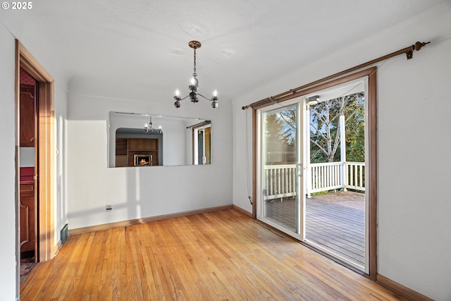 spare room with an inviting chandelier and light hardwood / wood-style flooring