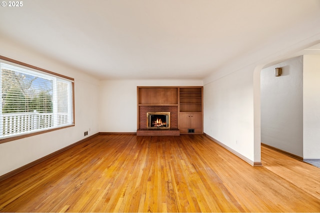 unfurnished living room featuring hardwood / wood-style floors and a brick fireplace