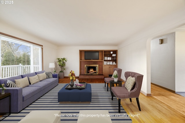 living room with hardwood / wood-style flooring and a brick fireplace