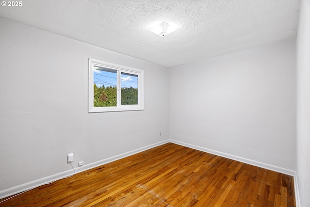 spare room featuring wood-type flooring and a textured ceiling