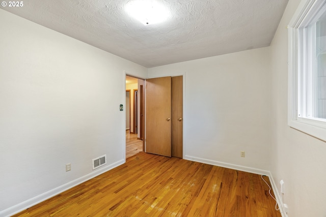 empty room featuring light hardwood / wood-style floors and a textured ceiling