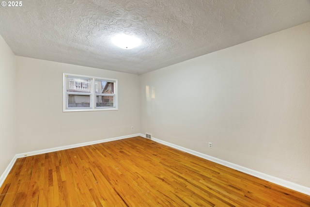 unfurnished room with wood-type flooring and a textured ceiling