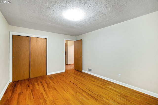 unfurnished bedroom with hardwood / wood-style flooring, a textured ceiling, and a closet