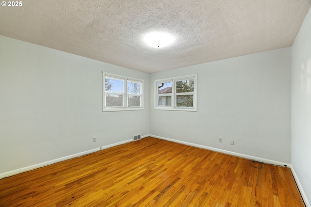 spare room featuring hardwood / wood-style floors and a textured ceiling