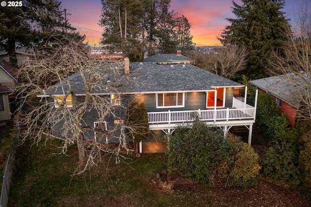 back house at dusk with a wooden deck