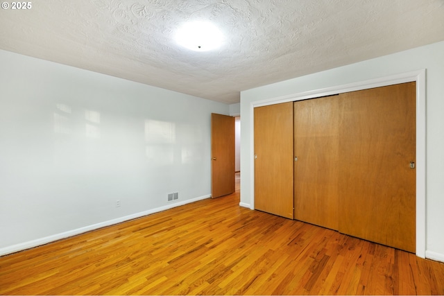 unfurnished bedroom featuring a closet, light hardwood / wood-style flooring, and a textured ceiling