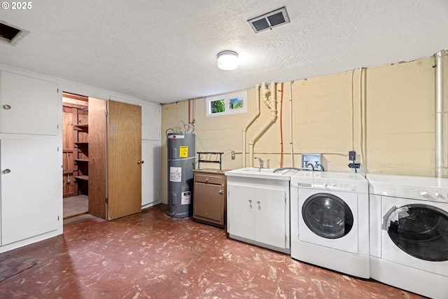 laundry area featuring sink, water heater, cabinets, a textured ceiling, and washing machine and clothes dryer