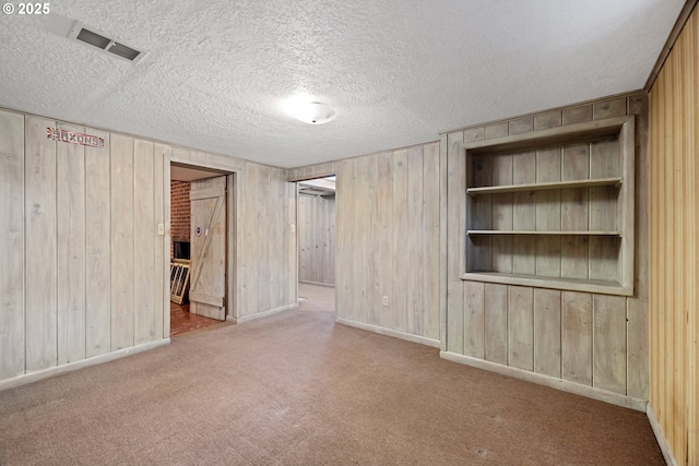 spare room with light carpet, a textured ceiling, and wood walls