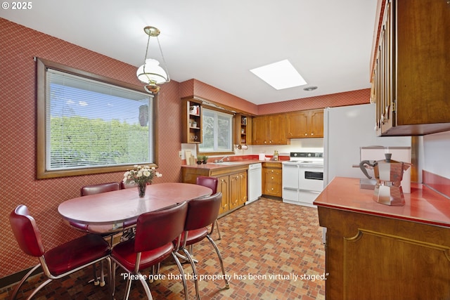 kitchen featuring pendant lighting, white appliances, a skylight, and sink